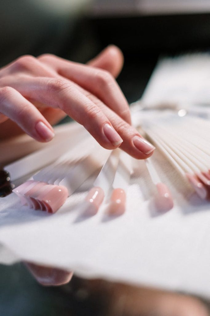 Close-up of a womans hand selecting nail polish colors in a beauty salon.